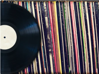 A vinyl record rests on top of multiple other vinyl records.